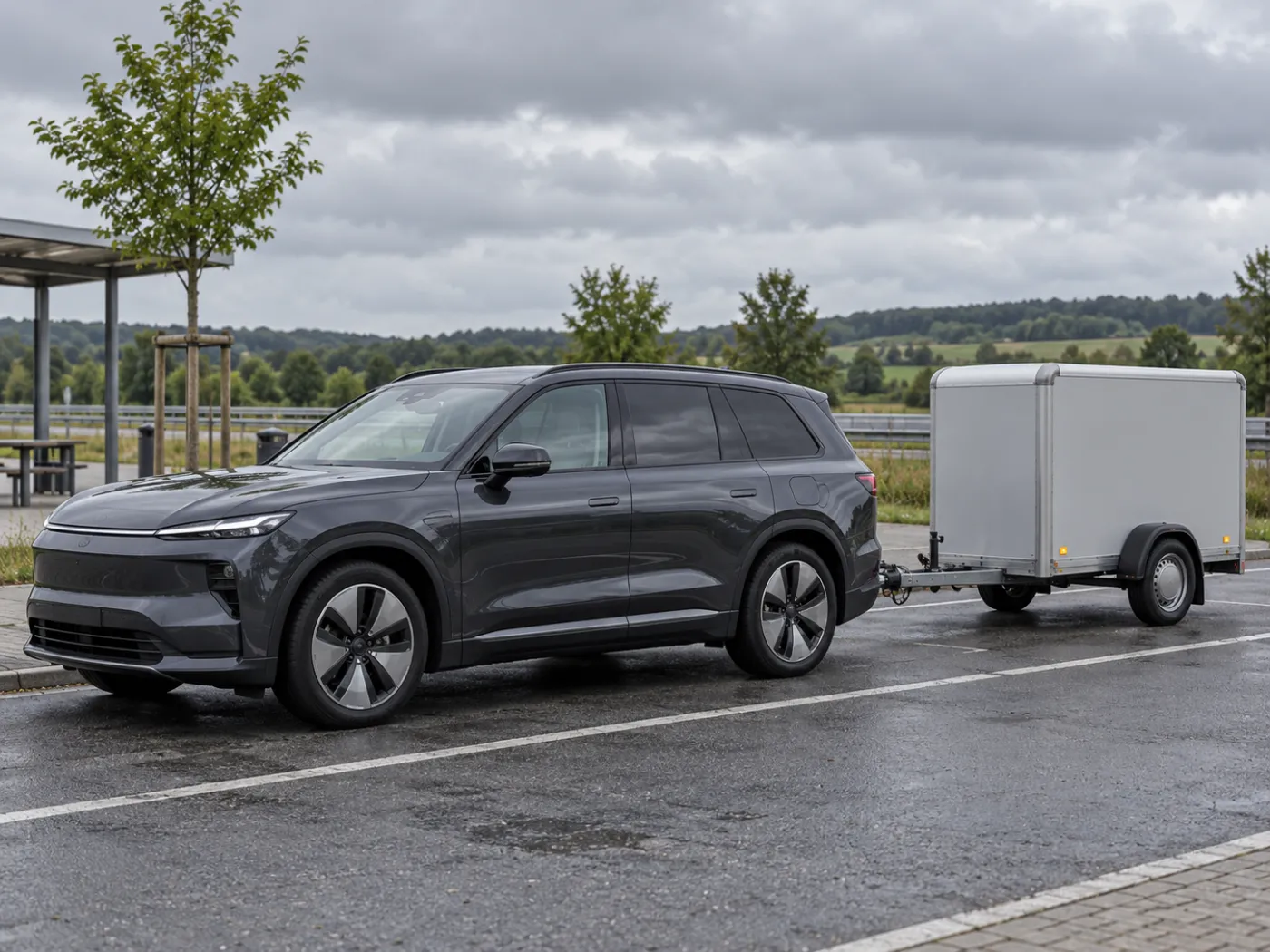 Großes Elektro-SUV mit Anhänger auf einem Rastplatz